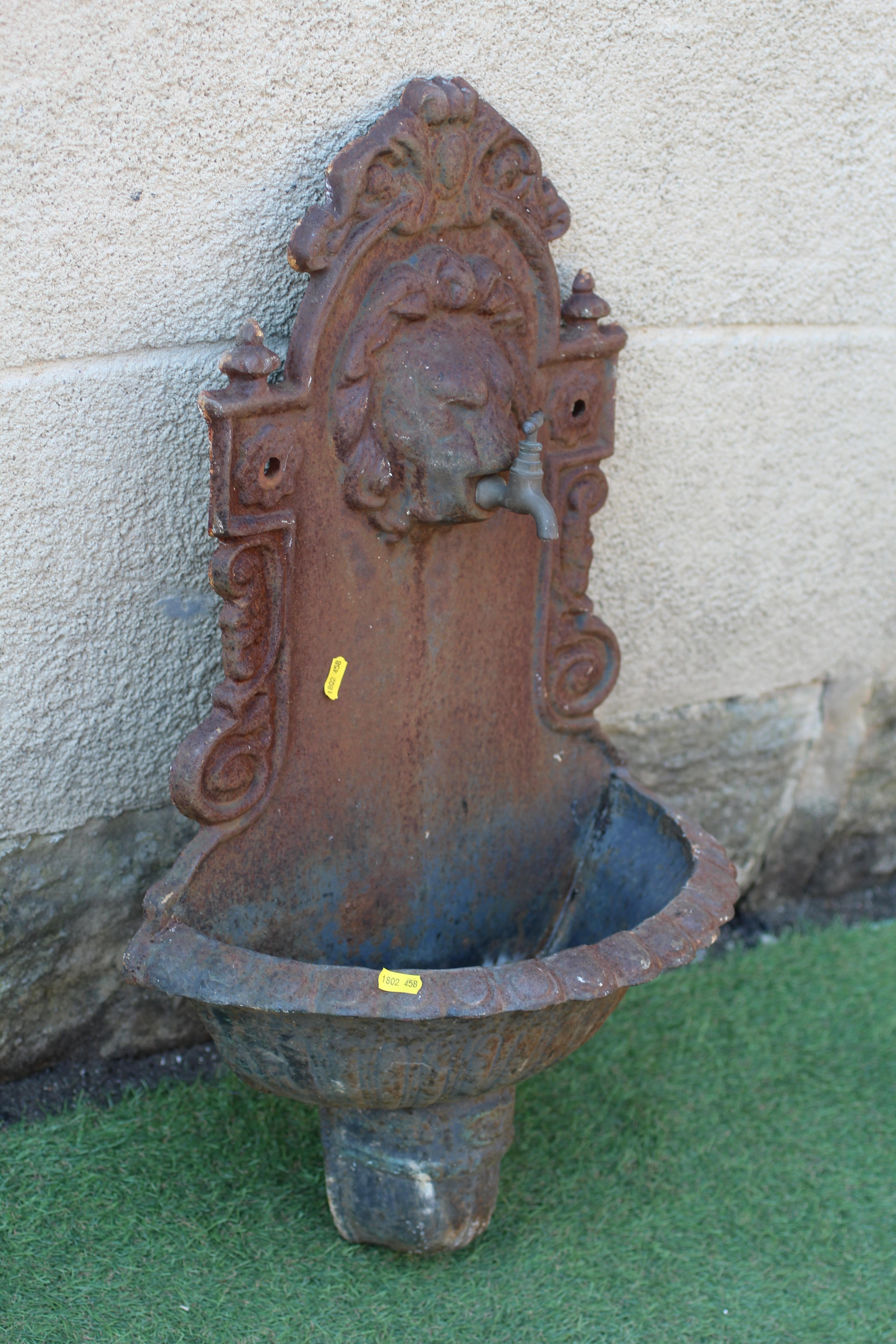 A SMALL CAST IRON WALL FOUNTAIN, the arched scroll edged back with lion head faucet, the bowl with Image