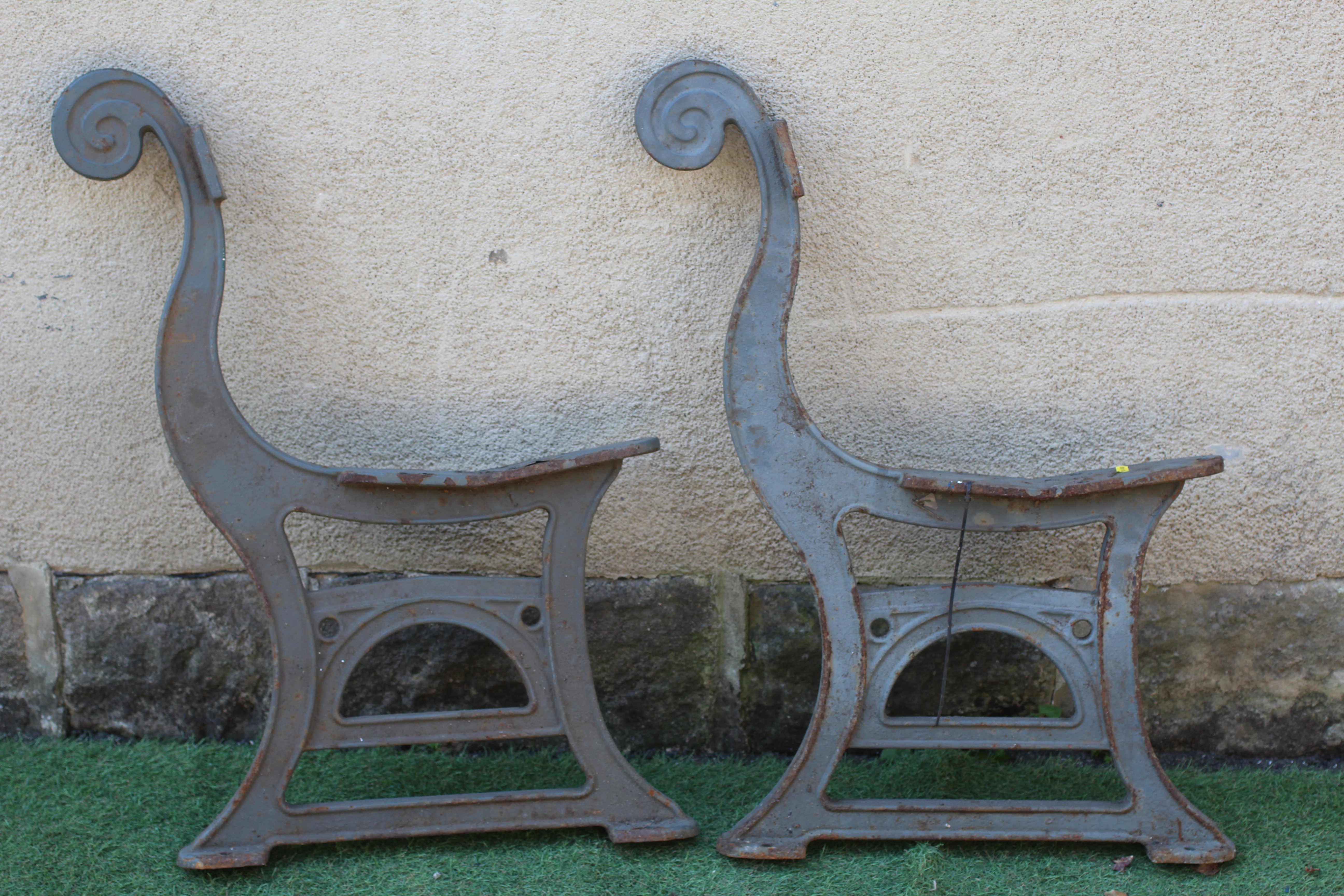 A PAIR OF CAST IRON BENCH ENDS, c.1900, with scrolled back, the channelled base with arched panel Image