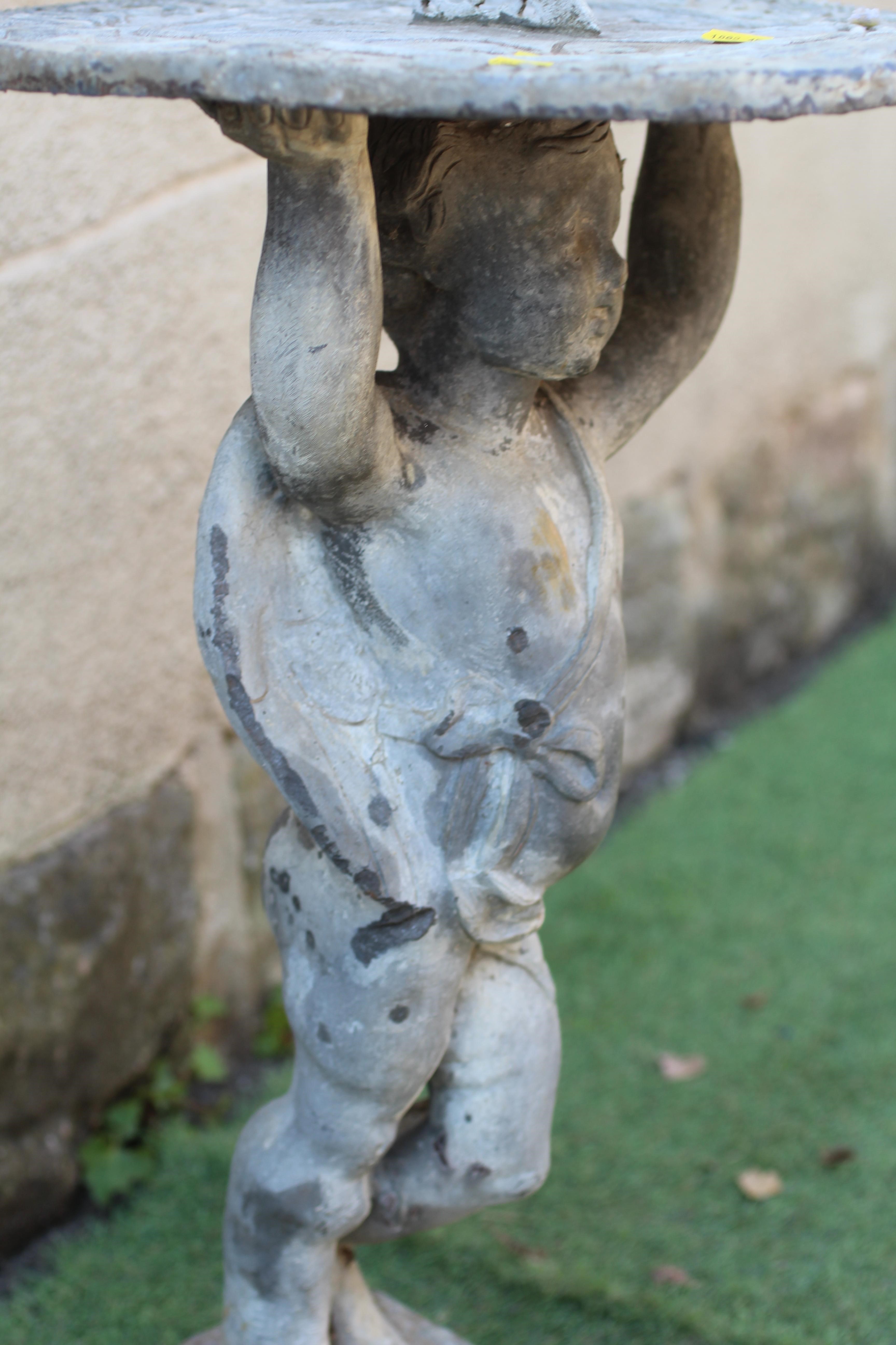 A LEAD FIGURAL SUNDIAL, modern, held aloft by a cherub, on domed base, 16 1/2" w x 31" h Image