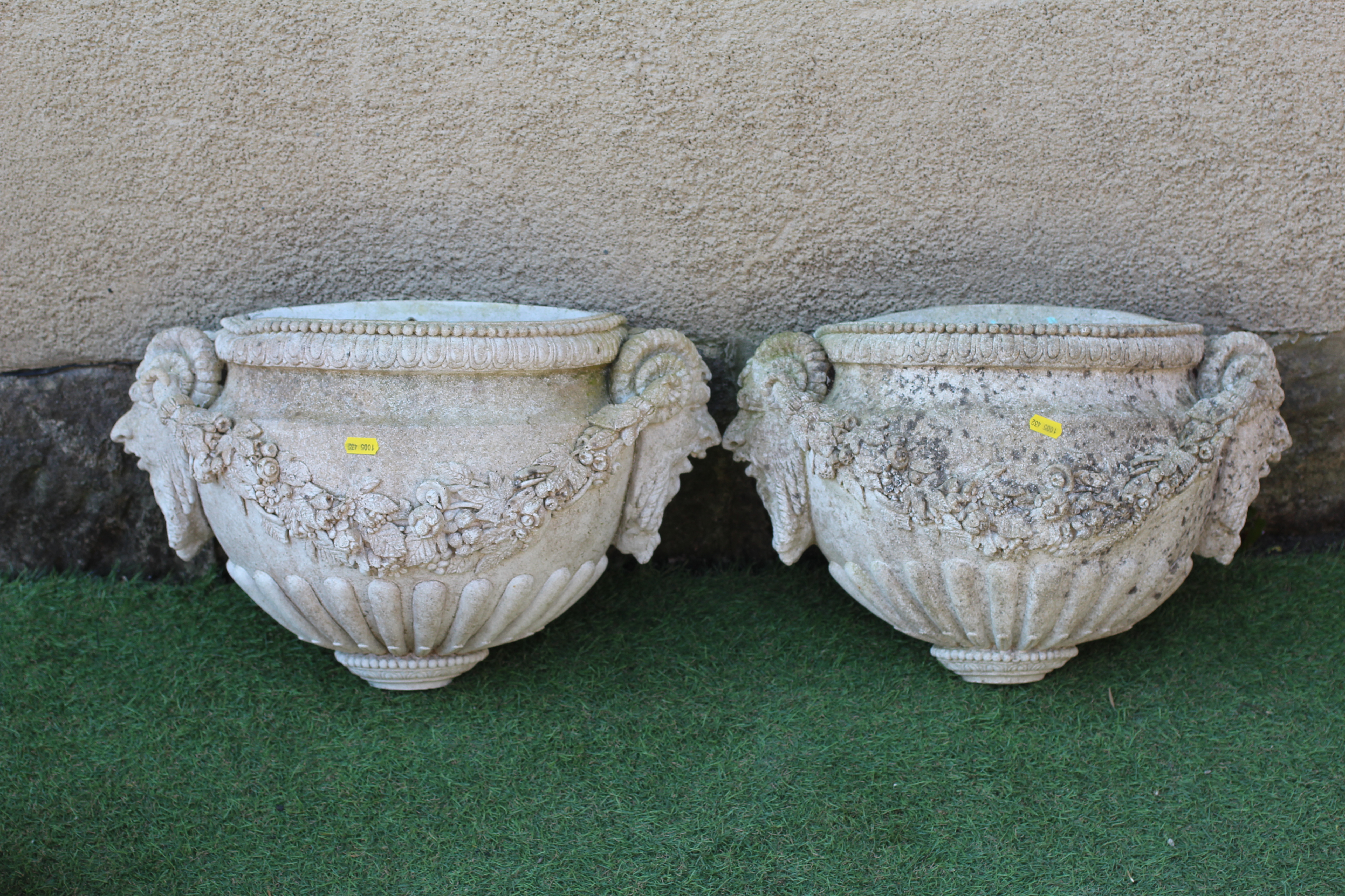 A PAIR OF CAST STONE WALL PLANTERS of demi lune half fluted form with Bacchanalian masks at either Image