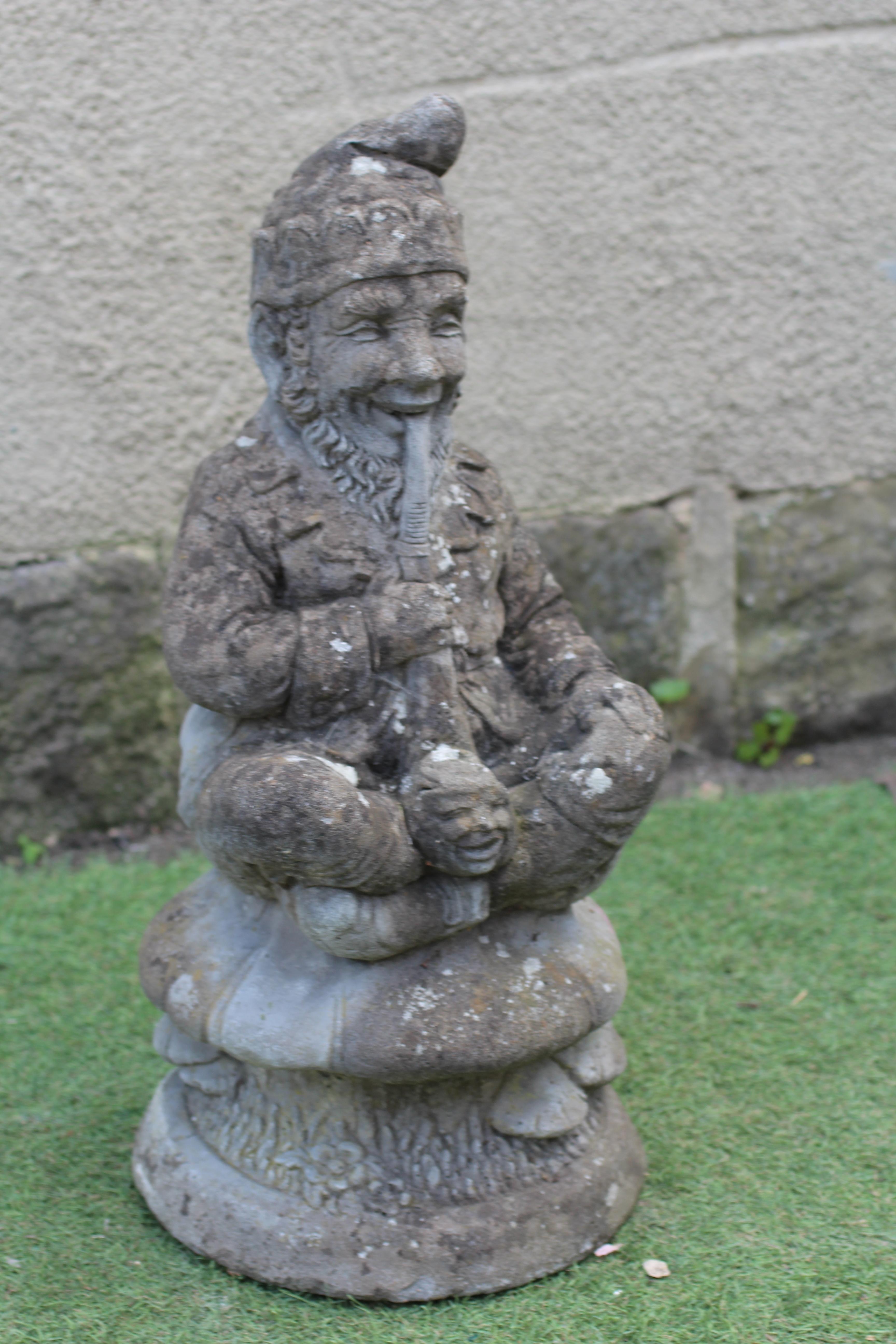 A CAST STONE GNOME seated on a toadstool and smoking a pipe, 24 1/2" high Image