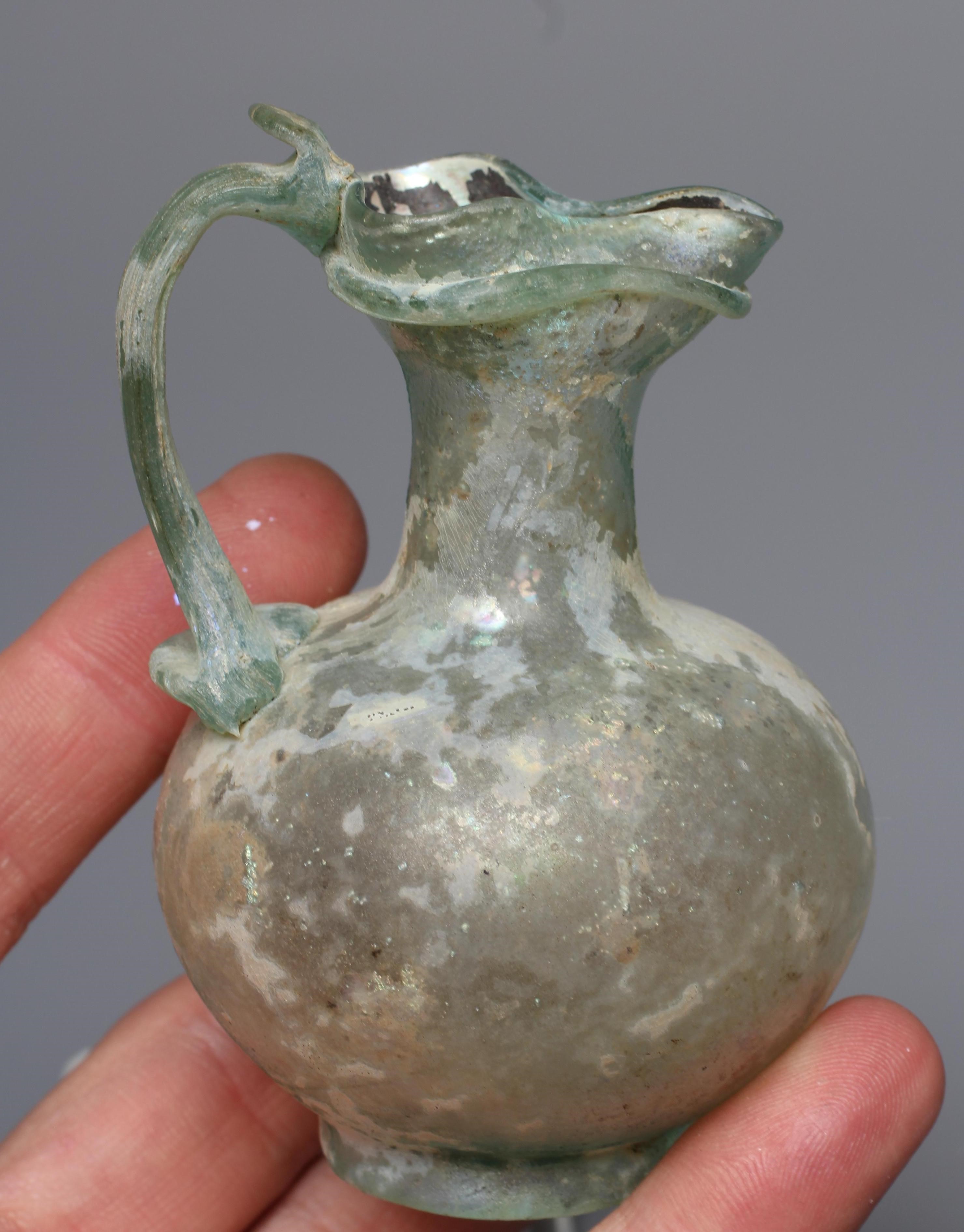 A ROMAN GREEN GLASS JUG, 3rd-4th century AD, with trefoil lip and pulled handle, 3 1/2" high, Image