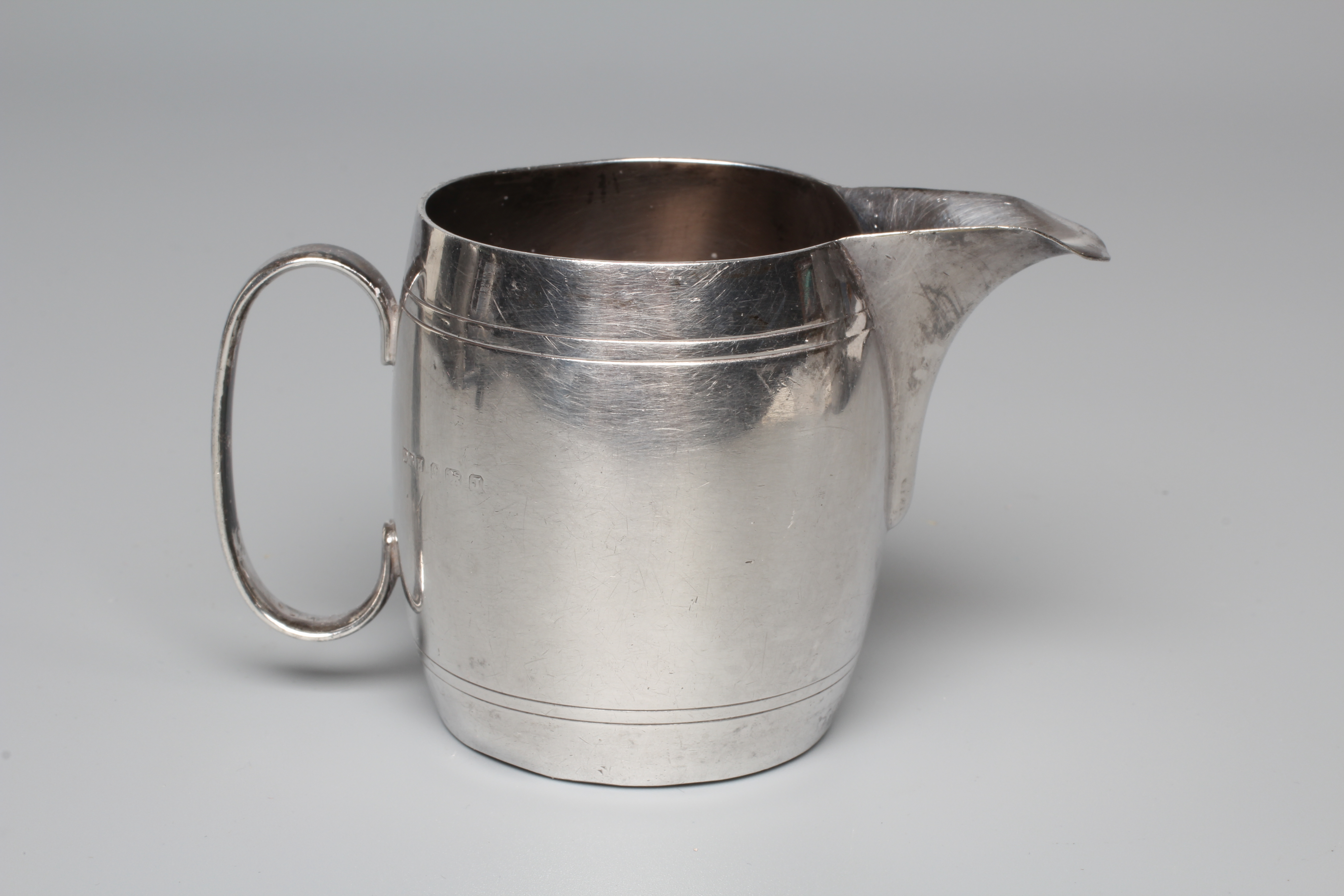 A GEORGE V ART DECO CREAM JUG by Deykin & Harrison, Birmingham 1933, of barrel form with engraved Image