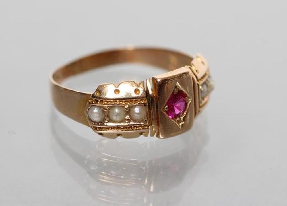 A LATE VICTORIAN 15CT GOLD RING centred by a gypsy set ruby within panelled shoulders each set with Image