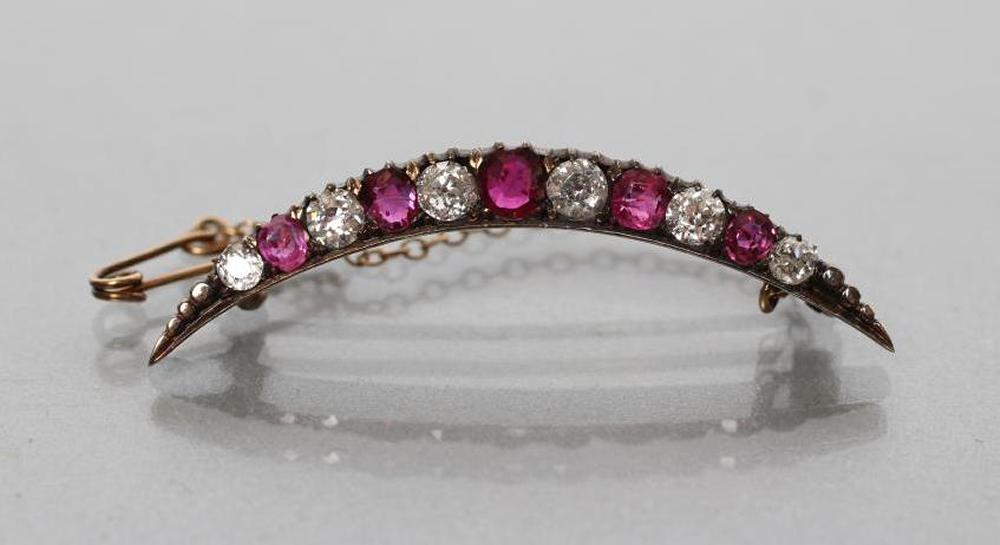 AN EDWARDIAN RUBY AND DIAMOND CRESCENT BROOCH alternately claw set with five graduated rubies and Image