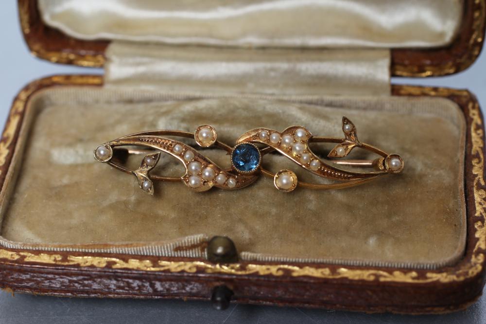 A LATE VICTORIAN BROOCH centred by an open back collet set round sapphire within seed pearl set Image