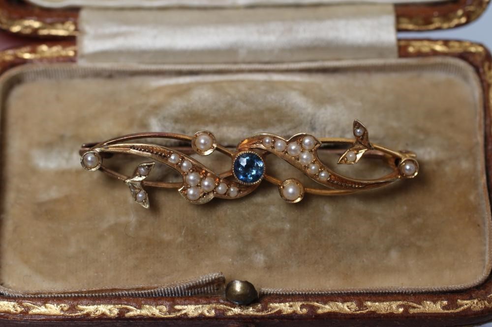 A LATE VICTORIAN BROOCH centred by an open back collet set round sapphire within seed pearl set Image