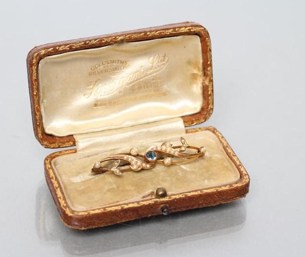 A LATE VICTORIAN BROOCH centred by an open back collet set round sapphire within seed pearl set Image
