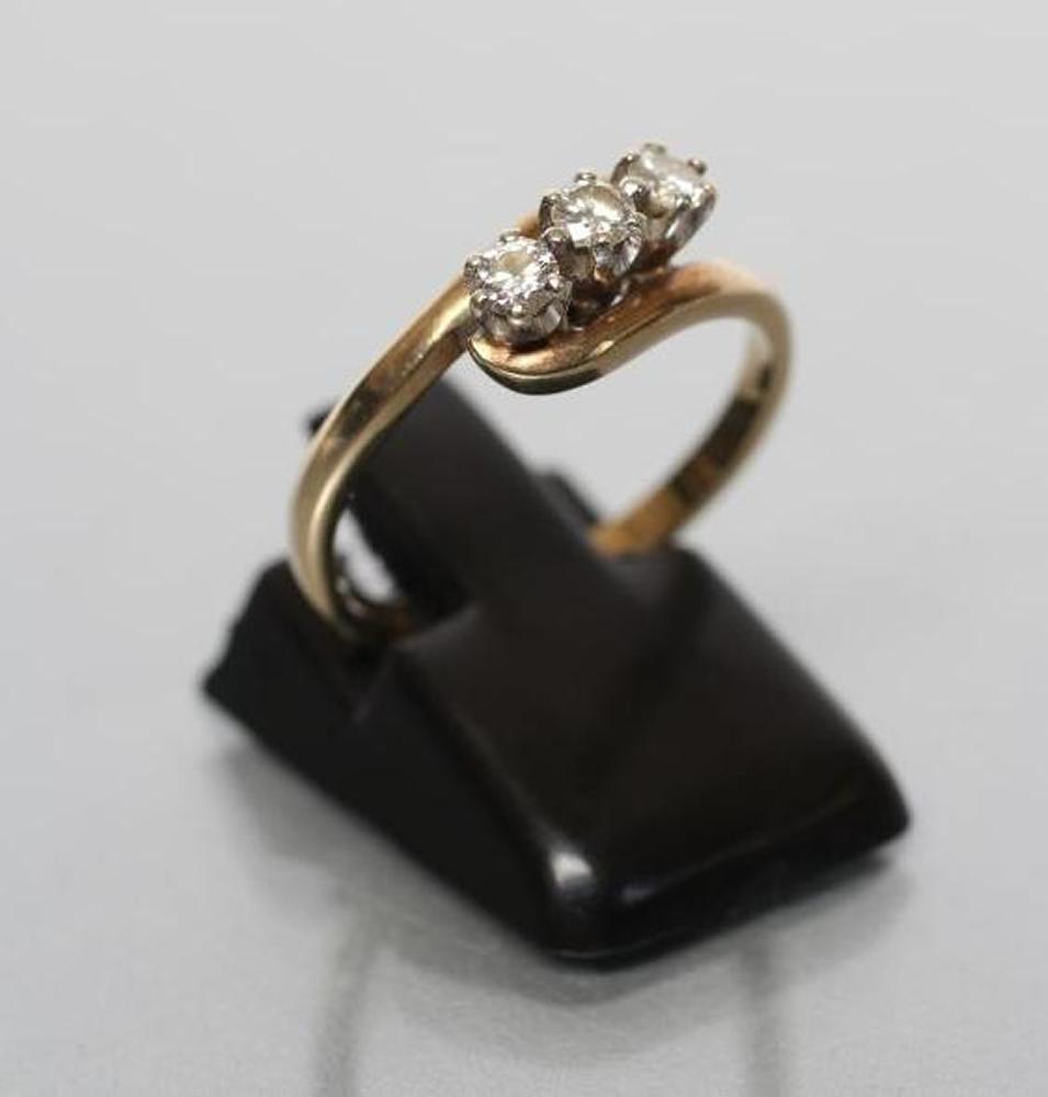 A THREE STONE DIAMOND CROSSOVER RING Image