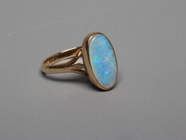 AN OPAL DRESS RING, the oval cabochon polished stone collet set to a plain shank stamped 14k, WK, Image