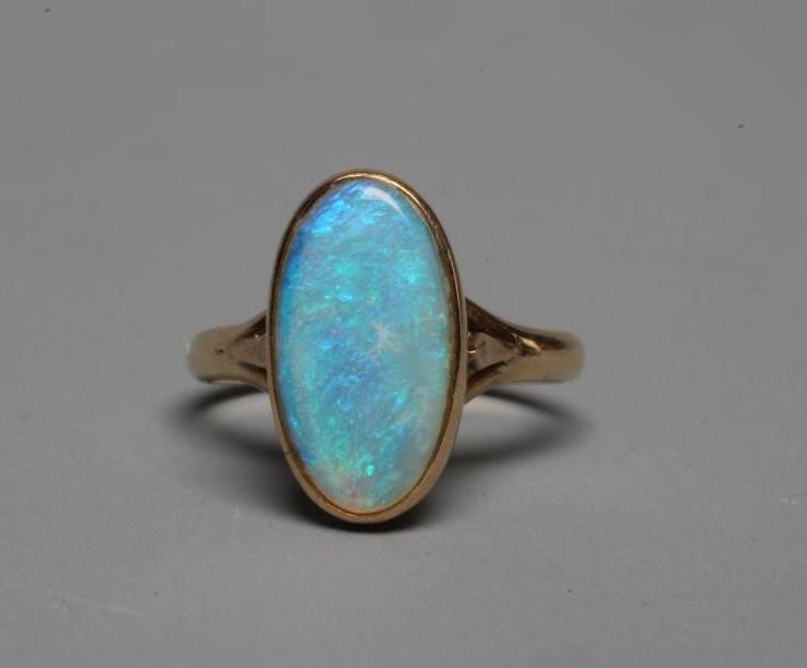AN OPAL DRESS RING, the oval cabochon polished stone collet set to a plain shank stamped 14k, WK, Image