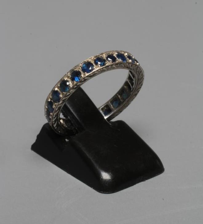 A SAPPHIRE ETERNITY RING, the numerous small circular facet cut stones point set to a leaf engraved Image