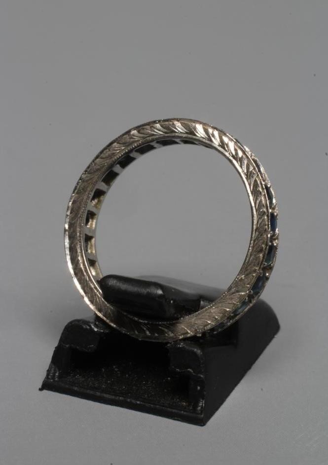 A SAPPHIRE ETERNITY RING, the numerous small circular facet cut stones point set to a leaf engraved Image