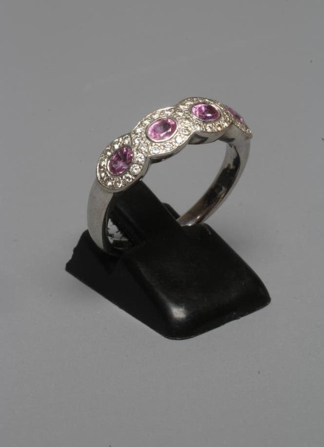 A HALF HOOP DRESS RING, the four collet set pink topaz (?) within borders of small point set Image