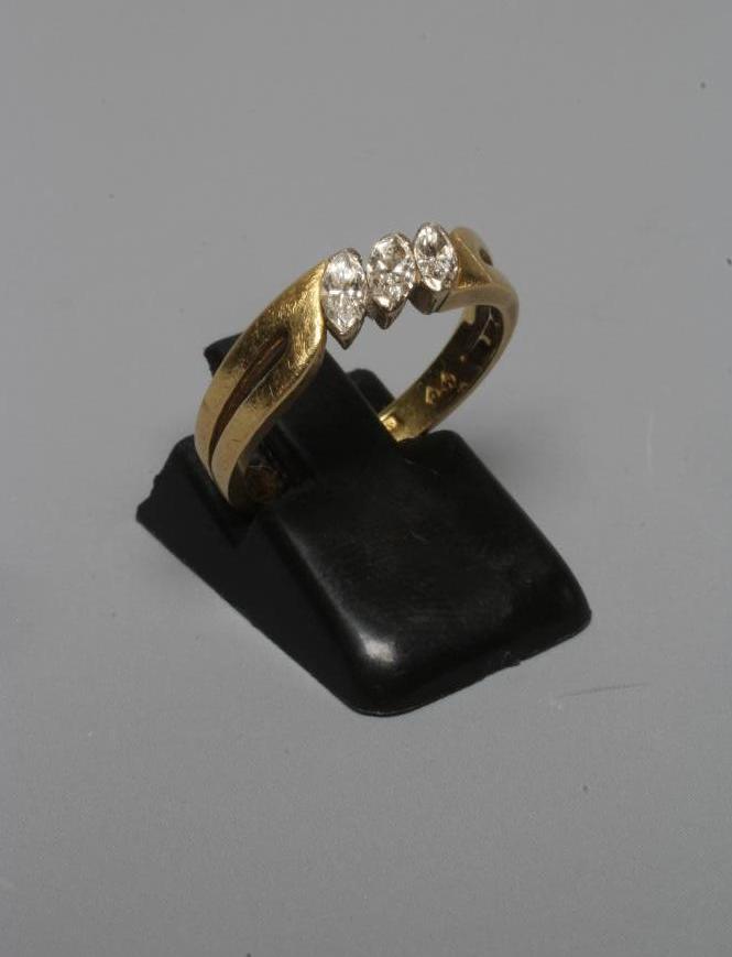A THREE STONE DIAMOND RING, the marquise cut stones claw set to open shoulders and a plain 18ct gold Image