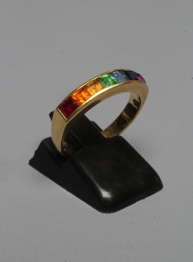 A MULTI-GEM HALF HOOP RING, the seven square cut stones including garnet, aquamarine and amethyst Image