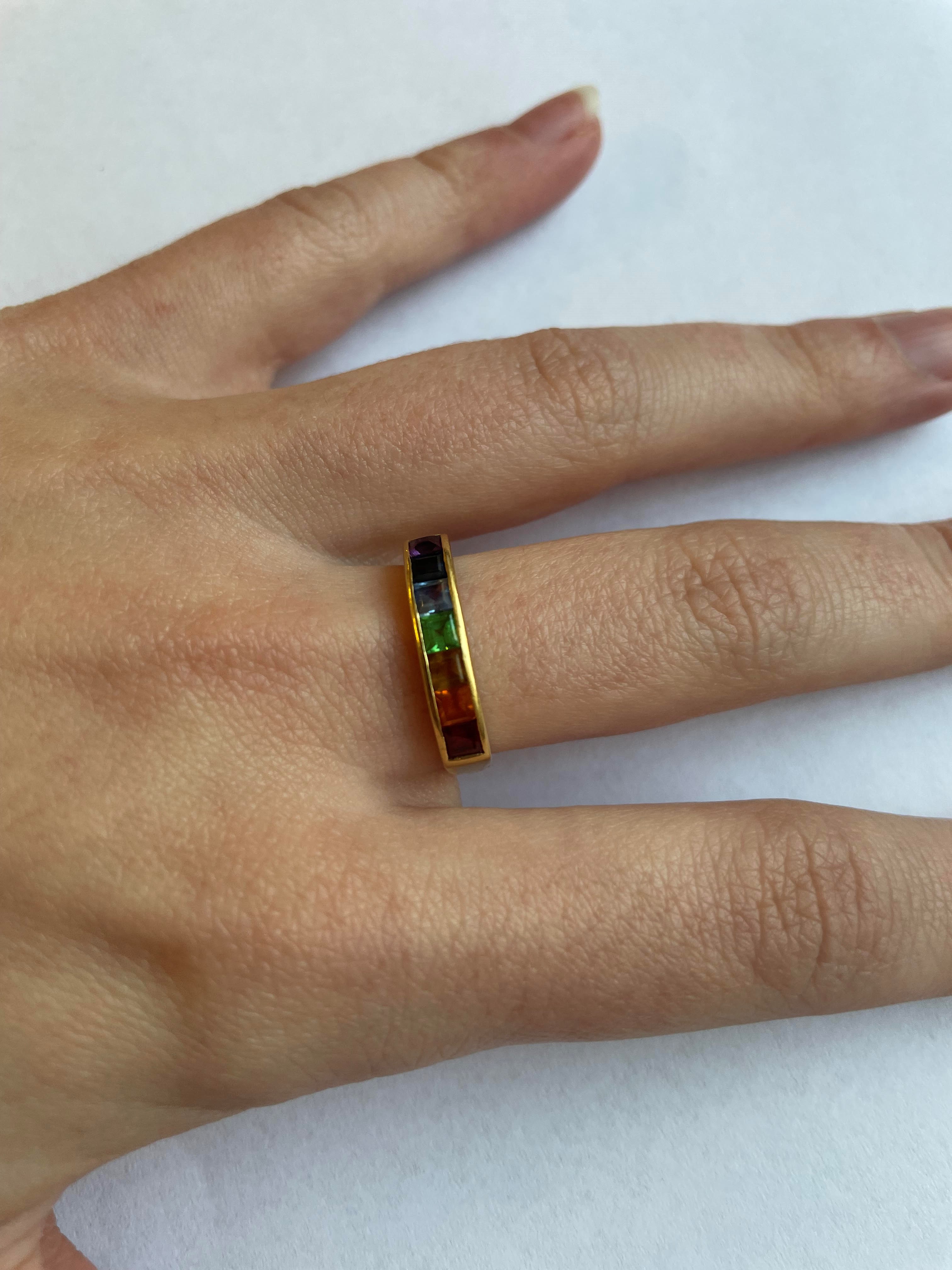 A MULTI-GEM HALF HOOP RING, the seven square cut stones including garnet, aquamarine and amethyst Image