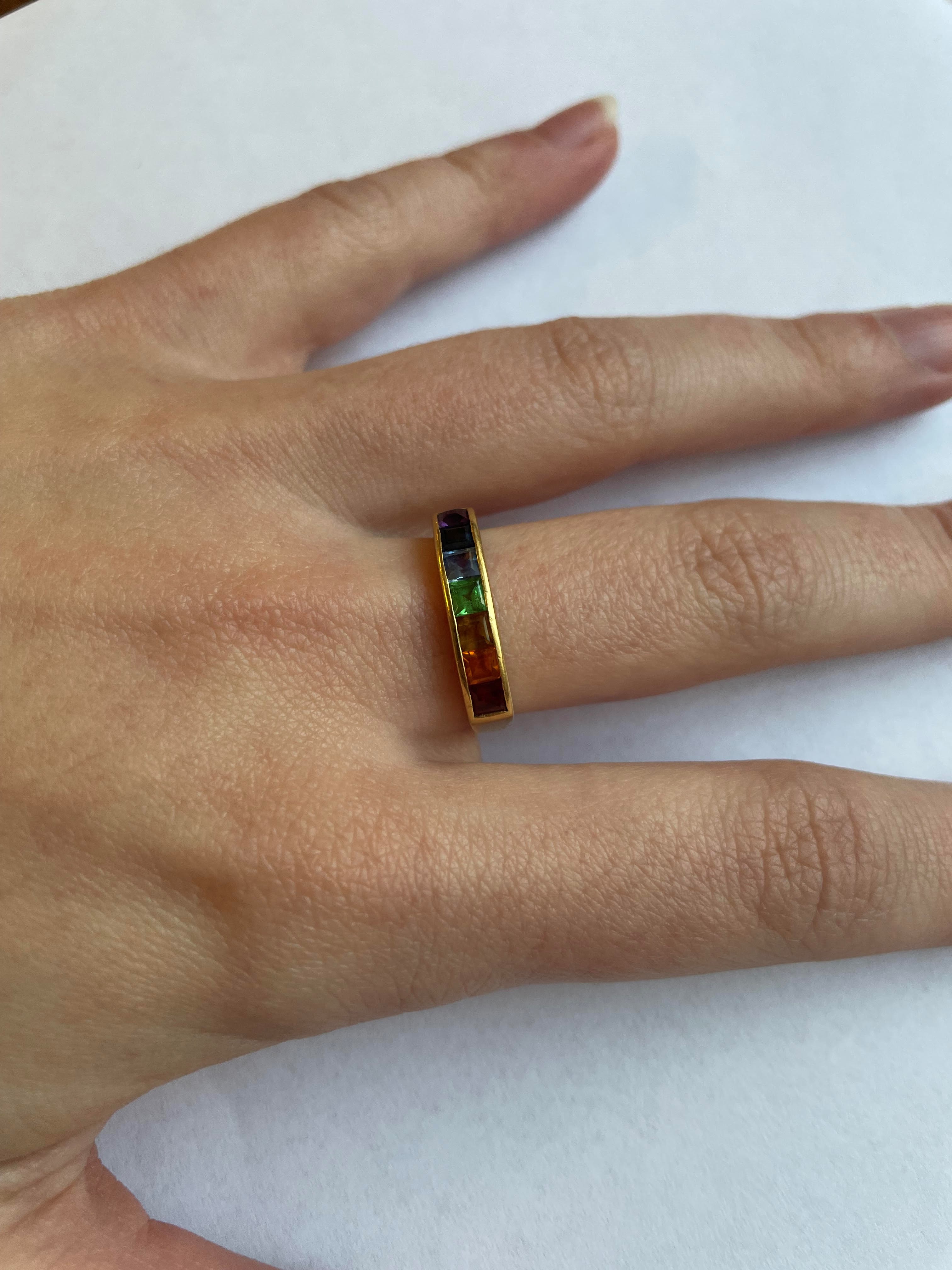 A MULTI-GEM HALF HOOP RING, the seven square cut stones including garnet, aquamarine and amethyst Image