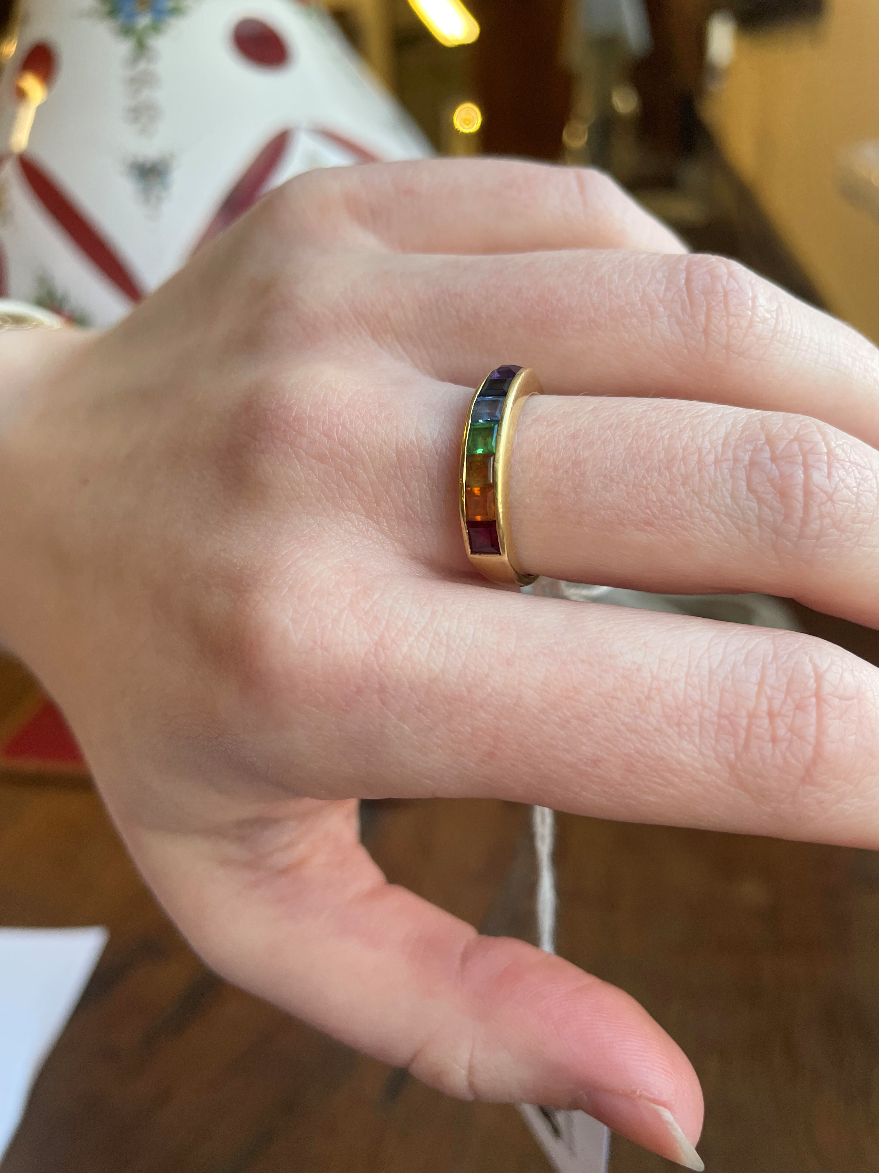 A MULTI-GEM HALF HOOP RING, the seven square cut stones including garnet, aquamarine and amethyst Image