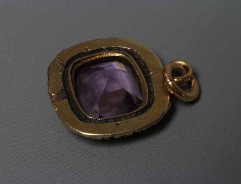 A VICTORIAN AMETHYST PENDANT, the facet cut cushion shaped stone collet set in a foliate carved Image