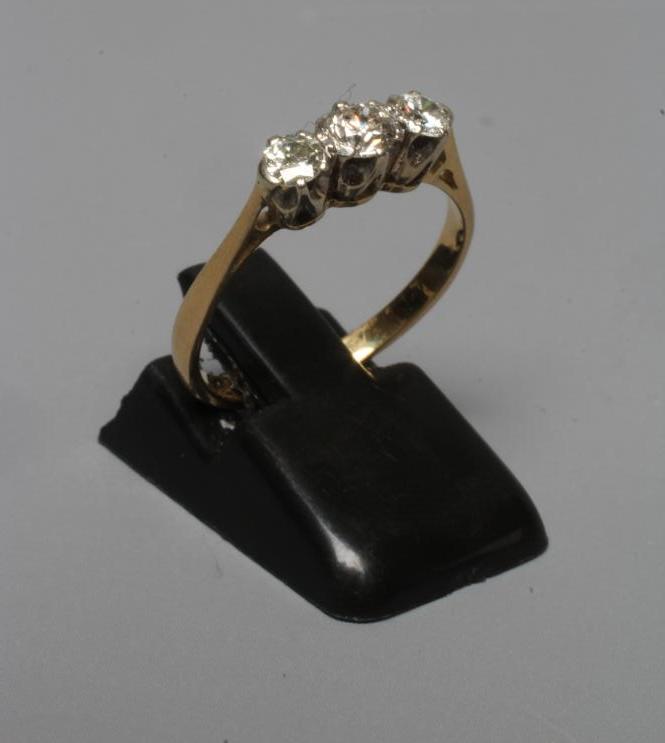 A THREE STONE DIAMOND RING, the brilliant cut stones claw set to a plain shank stamped 18ct, size N Image