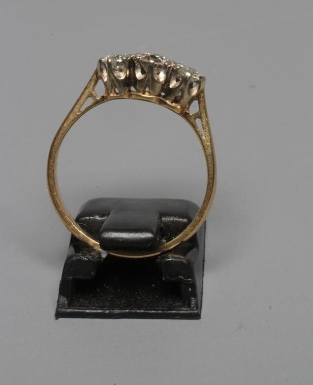 A THREE STONE DIAMOND RING, the brilliant cut stones claw set to a plain shank stamped 18ct, size N Image