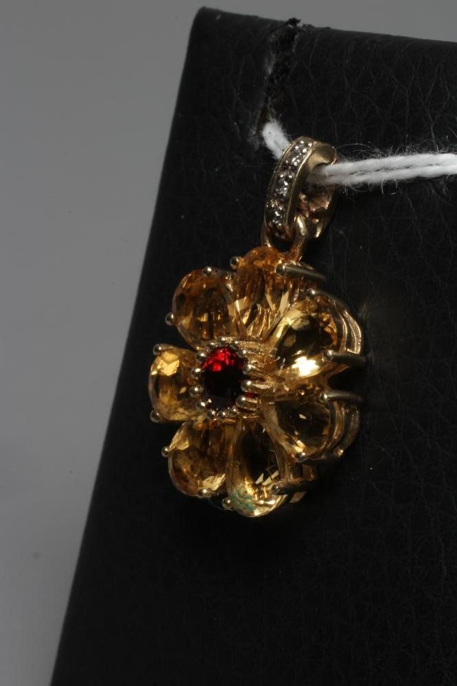 A MULTI-GEM FLOWERHEAD CLUSTER PENDANT centred by a circular facet cut garnet with seven citrine Image