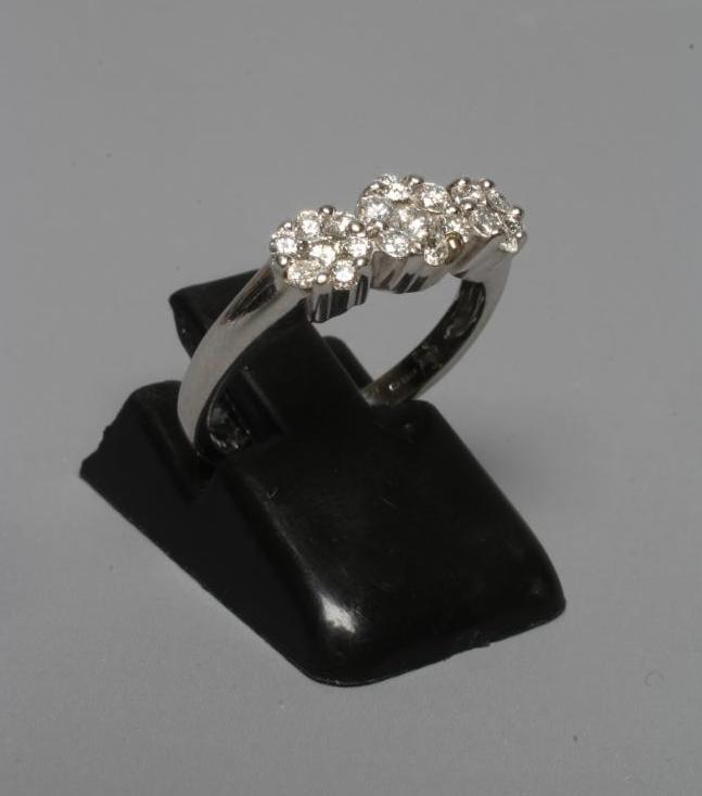 A DIAMOND TRIPLE CLUSTER RING, the brilliant cut stones claw set to plain shoulders and a white Image