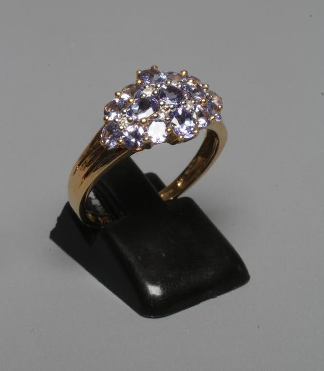 A TANZANITE DRESS RING, the mixed cut stones with six small diamond spacers to a plain shank, Image