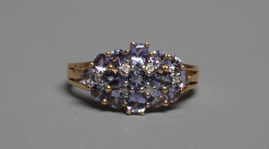 A TANZANITE DRESS RING, the mixed cut stones with six small diamond spacers to a plain shank, Image