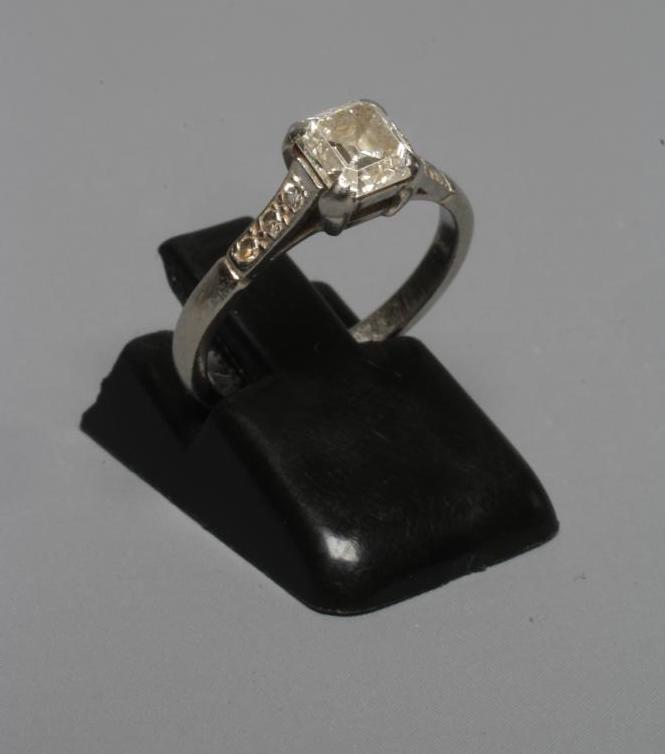 A SOLITAIRE DIAMOND RING, the Princess cut stone claw set to shoulders each pave set with three Image