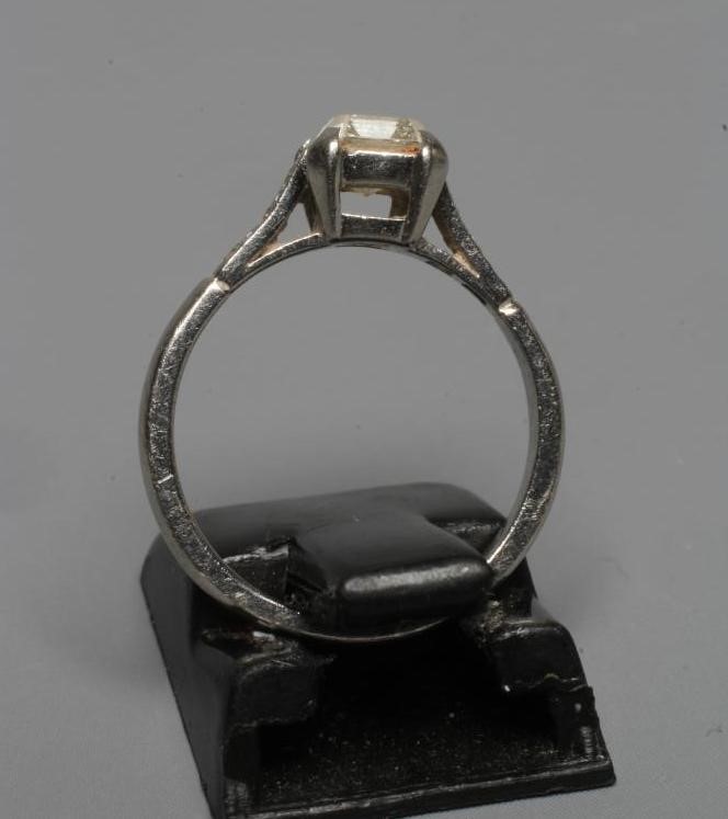 A SOLITAIRE DIAMOND RING, the Princess cut stone claw set to shoulders each pave set with three Image