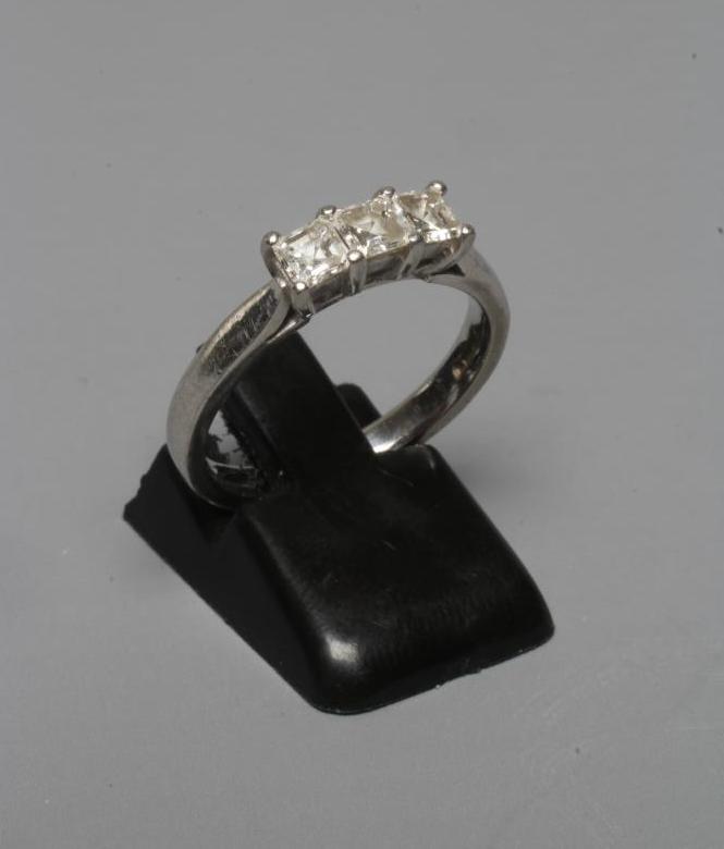 A THREE STONE DIAMOND RING, the Princess cut stones point set to a plain platinum shank, sponsor Image