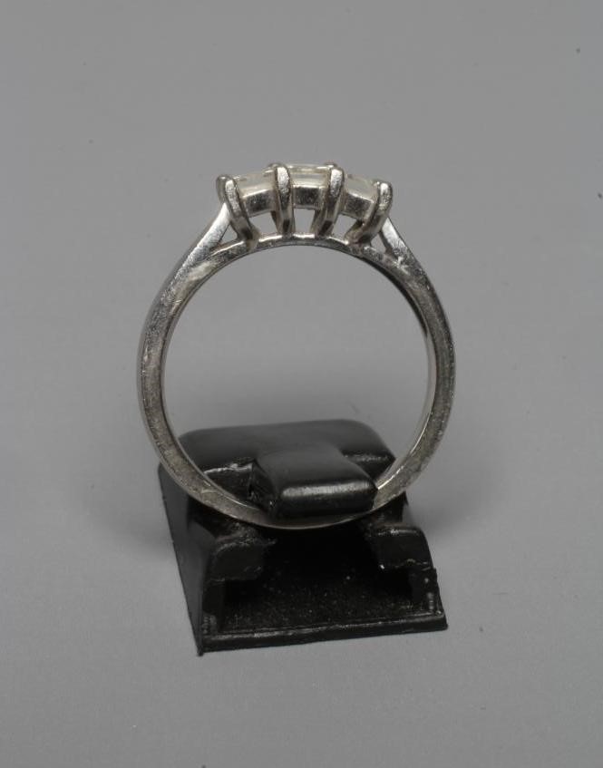 A THREE STONE DIAMOND RING, the Princess cut stones point set to a plain platinum shank, sponsor Image