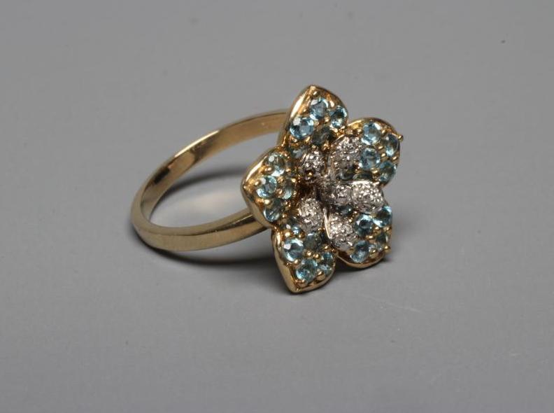 A MODERN FLOWERHEAD CLUSTER RING point set with small mix cut diamonds to the centre within blue Image
