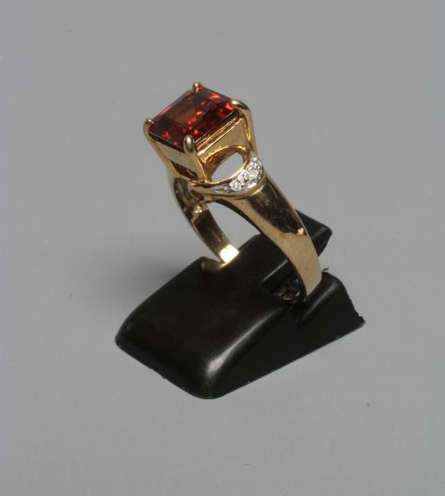 A DRESS RING, the claw set square cut garnet between open horseshoe shoulders each pave set with Image