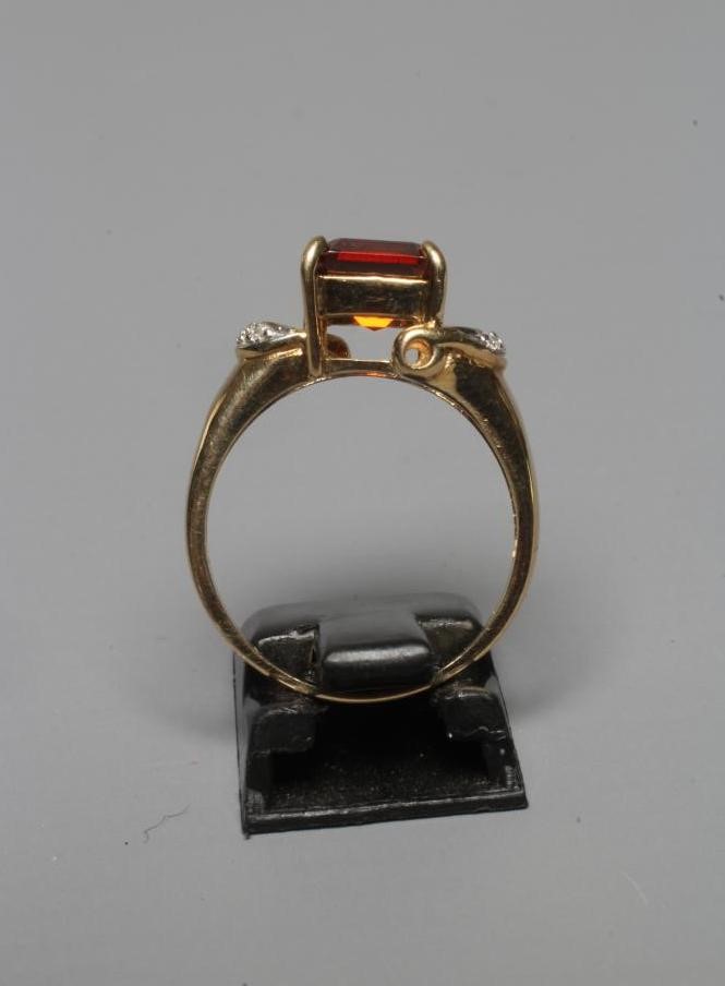 A DRESS RING, the claw set square cut garnet between open horseshoe shoulders each pave set with Image