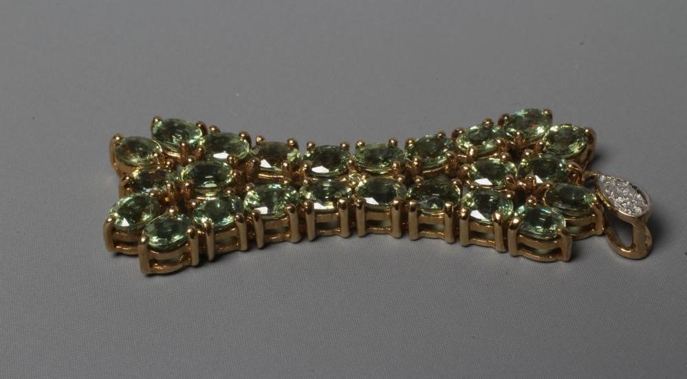 A PERIDOT PENDANT of stylised X form on a diamond point set tear drop bale, applied plaque stamped Image