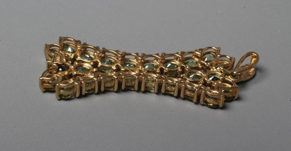 A PERIDOT PENDANT of stylised X form on a diamond point set tear drop bale, applied plaque stamped Image