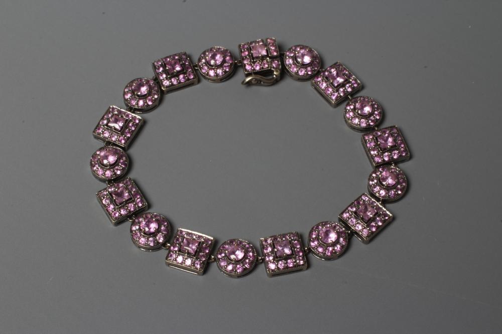 A PINK SAPPHIRE BRACELET with eight square and nine circular stone set clusters to a white frame Image