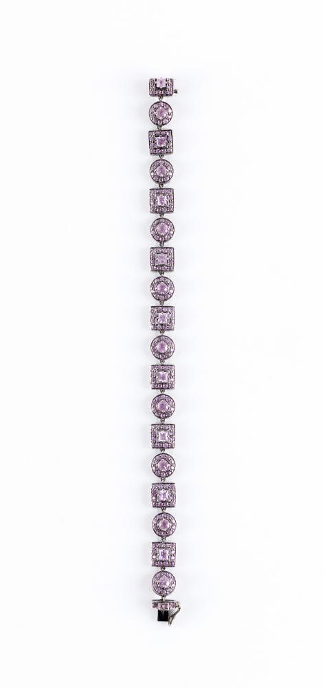 A PINK SAPPHIRE BRACELET with eight square and nine circular stone set clusters to a white frame Image