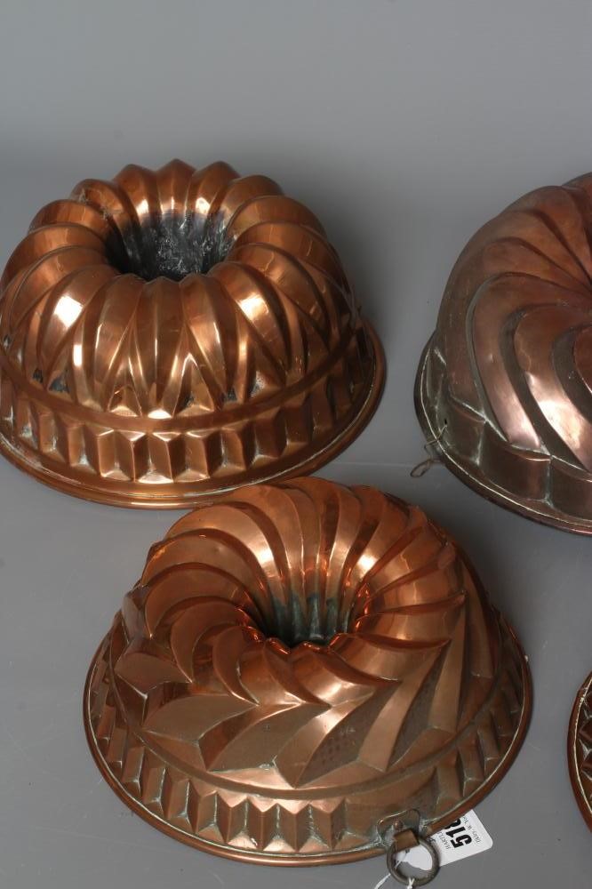 FIVE VICTORIAN COPPER BUNDT MOULDS comprising a pair with hanging loops, 10" diameter, a larger tin, Image