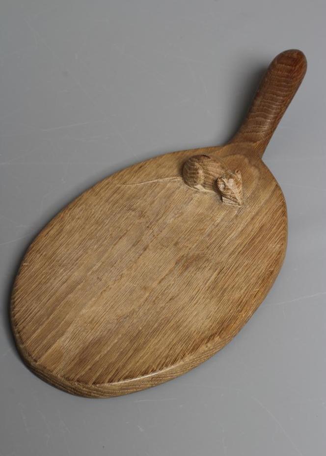 A ROBERT THOMPSON OAK CHEESEBOARD of oval form with carved mouse trademark in high relief, 14 1/2" Image