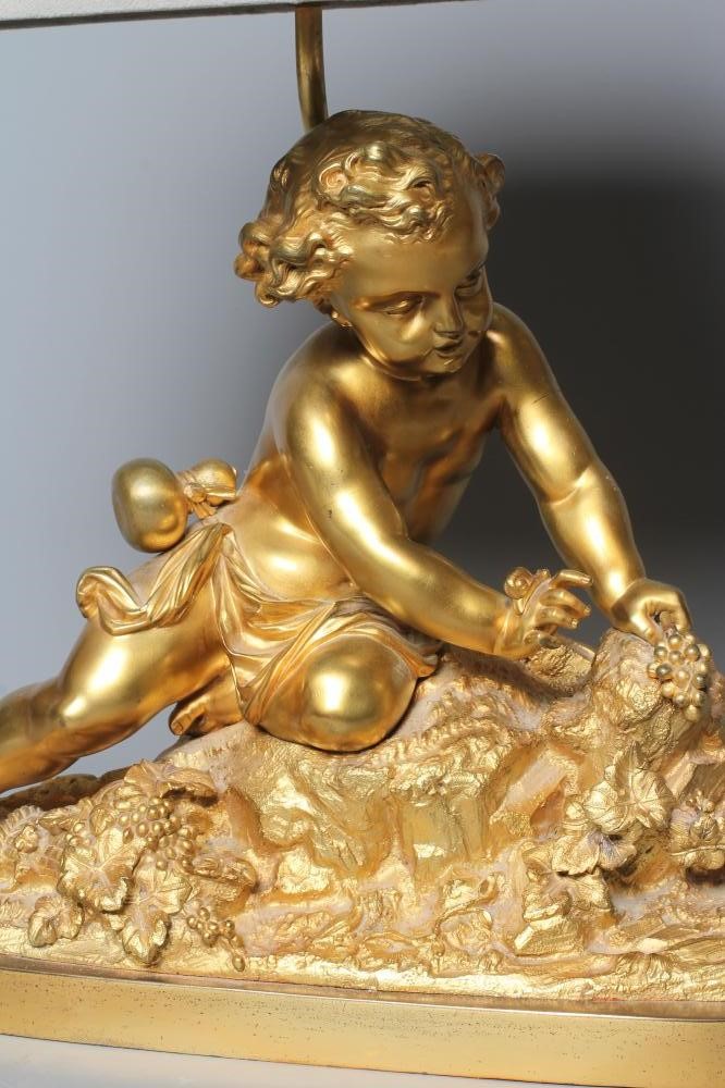 A GILT METAL AND COMPOSITION TABLE LAMP, 20th century, modelled as a cherub on a rocky outcrop Image