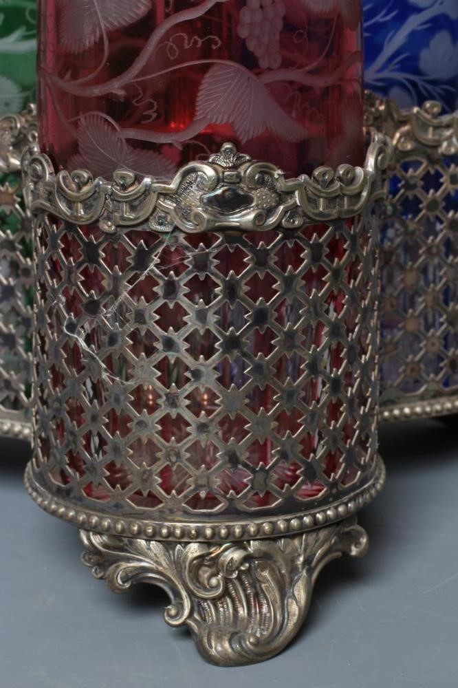 A SET OF THREE VICTORIAN COLOURED GLASS DECANTERS etched with fruiting vine Image