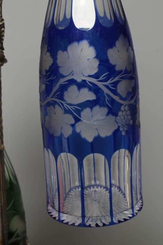 A SET OF THREE VICTORIAN COLOURED GLASS DECANTERS etched with fruiting vine Image