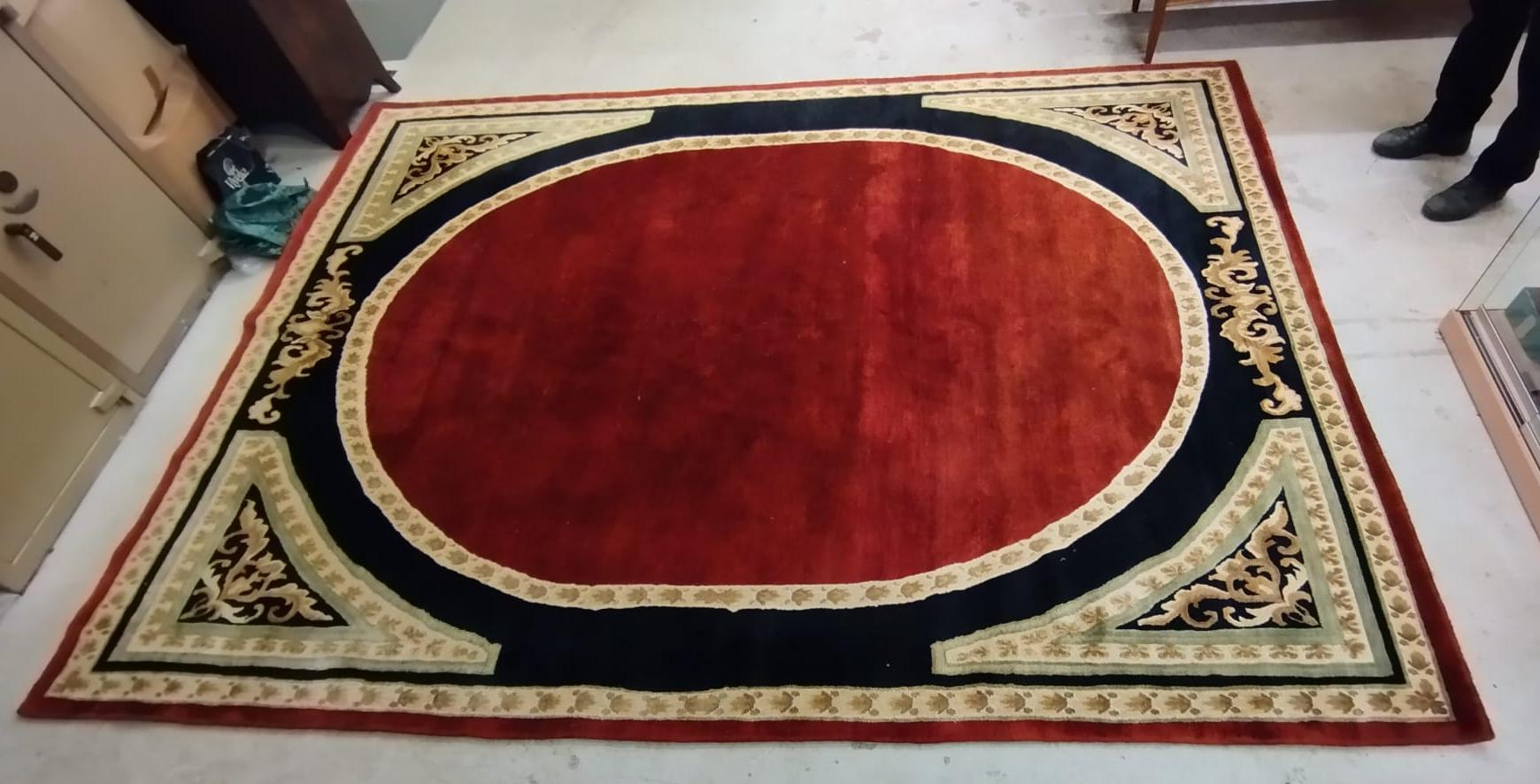 A WOOL RUG, modern, the black field centred by a large rust gul with cream border and conforming Image