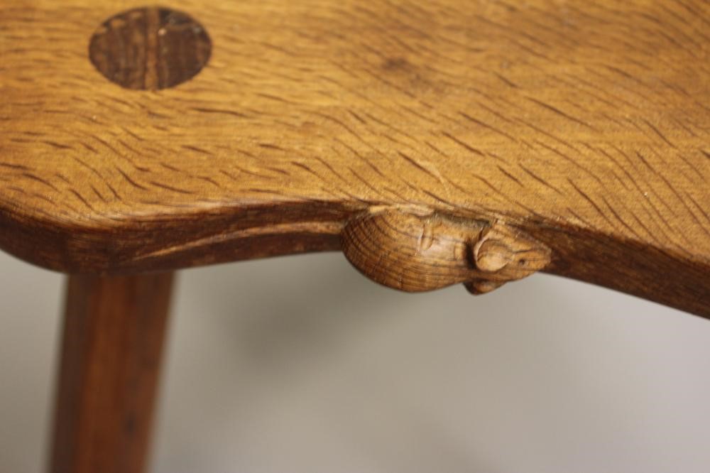 A ROBERT THOMPSON OAK COW STOOL, the kidney shaped seat raised on three splayed faceted legs, carved Image