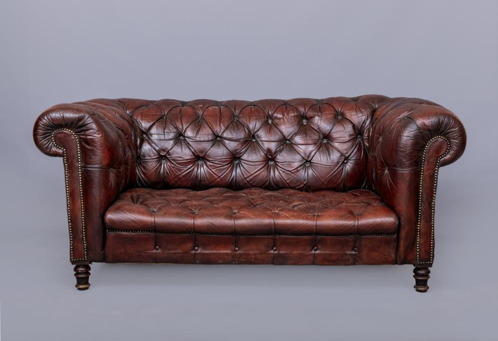 A RED LEATHER CHESTERFIELD SOFA, c.1900, button upholstered and close nailed, raised on turned Image