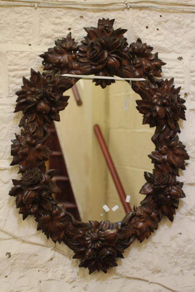 A CARVED OAK PIER GLASS, c.1900, the oval plate within a boldly carved frame with flowers and Image